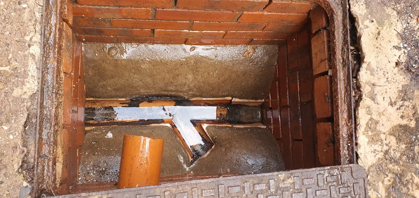 View inside a blocked drain manhole showing standing water.
