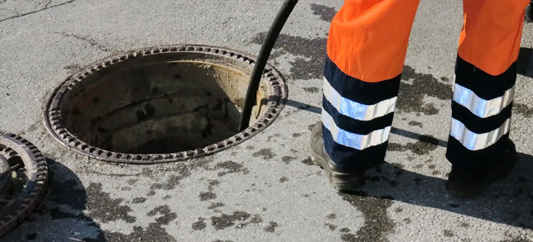 Drainage worker with equipment in an open manhole